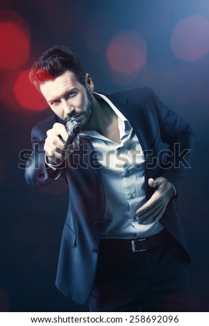 Cool aggressive man in shirt and jacket pointing a gun