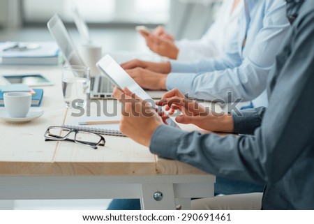 Business team working at office desk using a tablet, a laptop and a smart phone, hands close up, unrecognizable people