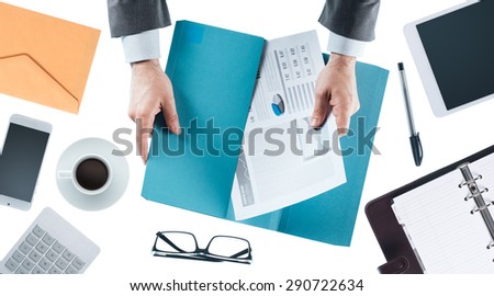 Businessman working at office desk and holding financial reports, hands close up, top view