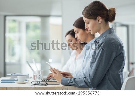 Efficient business women working together at office desk using laptops and mobile devices, women entrepreneurs concept