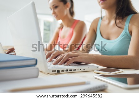 Young female students doing their summer homework at home using a laptop