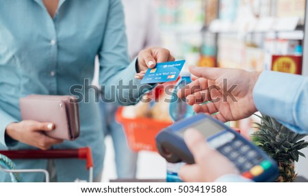 Woman at the supermarket checkout, she is paying using a credit card, shopping and retail concept Imagine de stoc © 