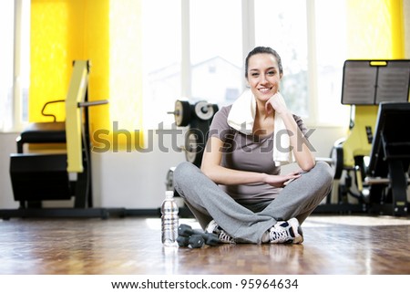 young woman sitting on the gym's floor after workout