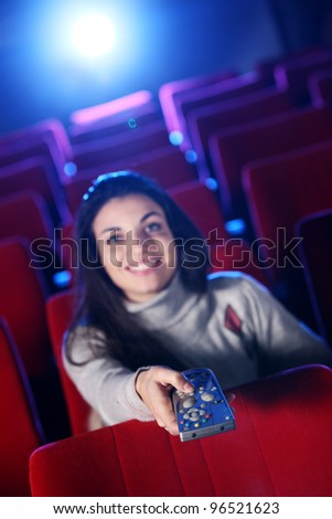 woman  holding a remote control TV, at a  movie theater. conceptual image