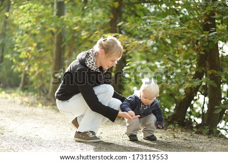 Happy moments: little boy with mother on outdoor walk in autumn park.