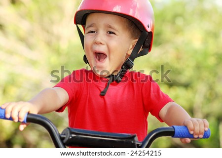 Little boy in red bike helmet riding his bike.