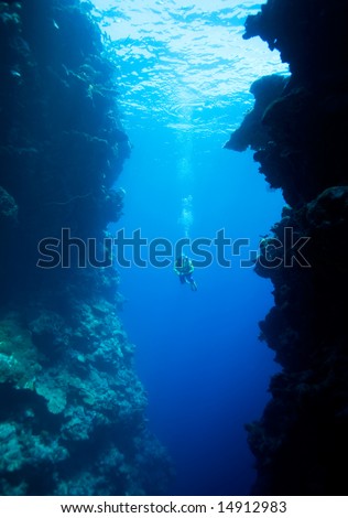 a female scuba diver, swimming into a large underwater cavern