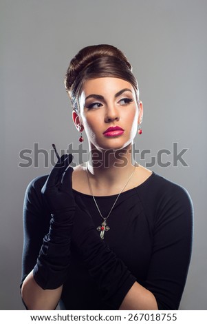Portrait of young woman in black dress holding a makeup brush