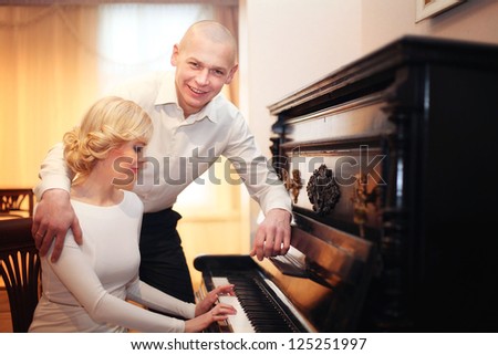 beautiful young man and woman sitting and playing the piano at the wedding