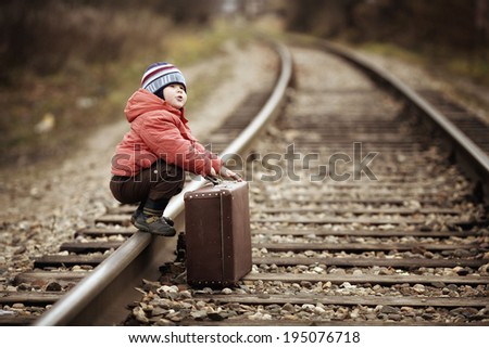 boy sitting in a suitcase near the railway journey