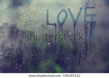 inscription love on the wet glass rain