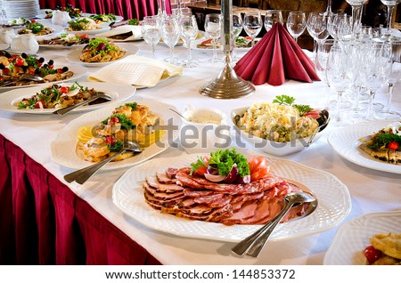 Elegant stylish display on a buffet table with platters of assorted cold meat and a variety of empty glassware at a catered event