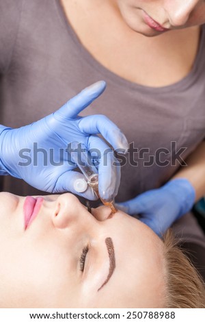 Cosmetologist applying anesthesia on eyebrows- eyebrow tattoo