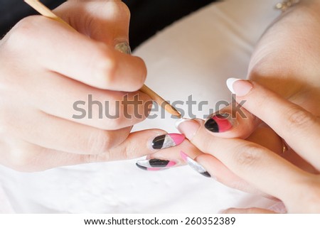 Professional manicurist applying liquid acrylic to nail extensions