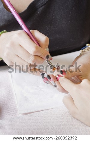 manicurist applying liquid acrylic to nail extensions