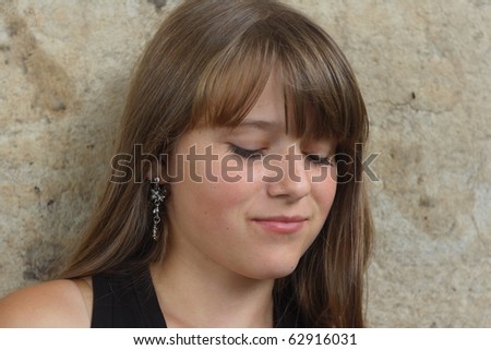 young girl with serenity expression against wall. look down