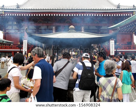 ASAKUSA, JAPAN-AUGUST 22, 2013: Centre of Sensoji temple forecourt is an incense burner. The visitors fanning smoke from the burning incense because believed to have healing power.Japan.August 22 2013
