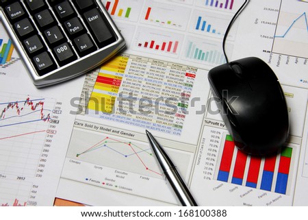 Business finance chart with number pad, silver pen and mouse on table.