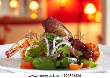 Salad shown close-up, in the background a dining room of a restaurant out of focus