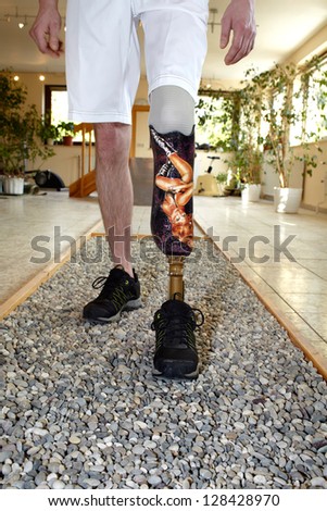 Male prosthesis wearer learning to walk in a special course or interior area where surfaces have been laid out to simulate realistic environmental situations