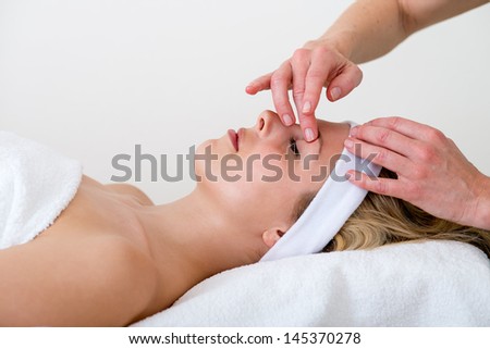 Masseuse massaging a woman eyebrow area. Masseuse massaging the eyebrow area of a relaxed beautiful blond woman