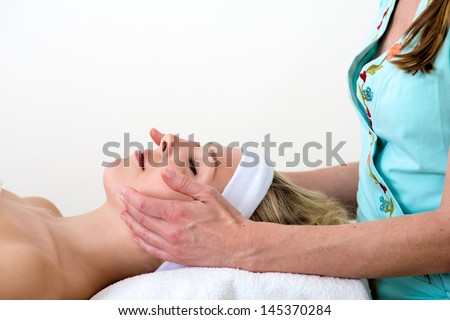 Masseuse performing a facial massage on a woman. Masseuse performing a facial massage on a relaxed beautiful blond woman