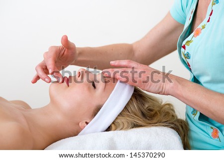 Masseuse massaging a woman lip area. Masseuse massaging the lower lip and chin area of a relaxed beautiful blond woman