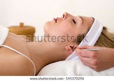 Homeopath applying auriculotherapy techniques. Alternative practitioner applying auriculotherapy or ear acupuncture techniques on the ear of a beautiful blond woman