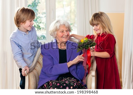 Grandma Receiving Flowers from Grandchildren looking very happy.