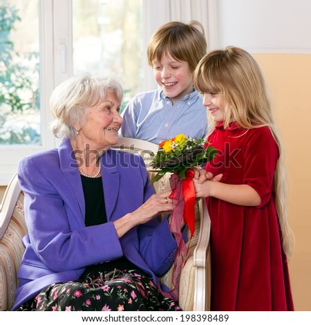 Children giving grandmother flowers as a gift