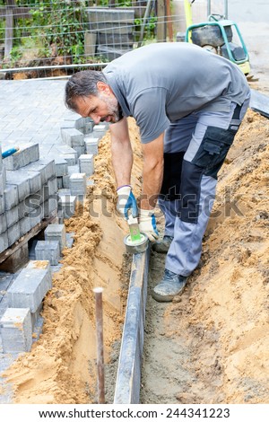 Construction worker puts stone slabs to mark a property and separate private property from street.