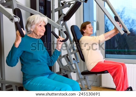 Two Senior Women Doing Chest Press Exercise at the Fitness Gym, Emphasizing Healthy Lifestyle.