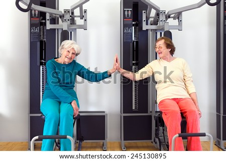 Happy Healthy Old Women Doing Seated Chest Pres Exercise at the Fitness Gym, Touching by Palms After.