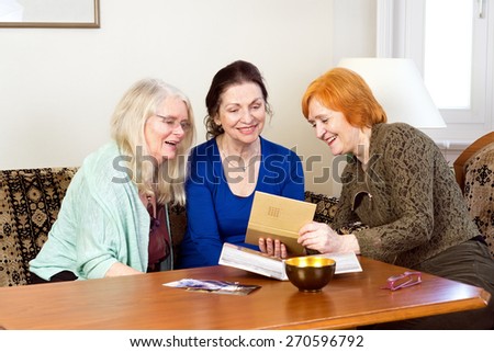 Three Happy Middle Age Women Sitting at the Living Area Looking at their Old Photograph in a Photo Album.