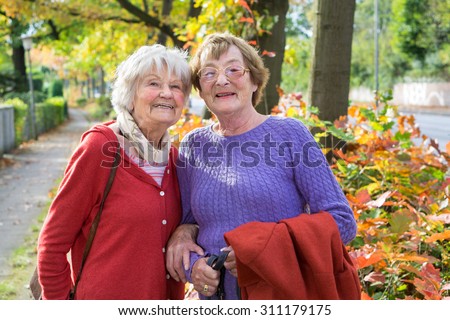 Half Body Shot of Two Happy Middle Aged Women in Autumn Outfits at the Pathway  Smiling at the Camera.