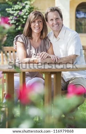 Attractive, romantic and happy middle aged man and woman couple in their forties, sitting together outside in a garden with flowers