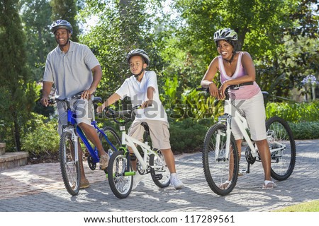 A young African American family, woman, man, father, mother & boy child riding bicycles in the summer