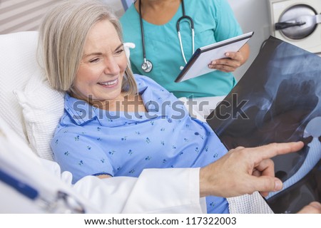 Happy senior woman patient recovering in hospital bed with male doctor and female nurse looking at hip replacement x-ray