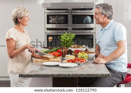 Man & woman couple preparing fresh healthy sandwiches in home kitchen with ham, cheese, salad lettuce and tomatoes