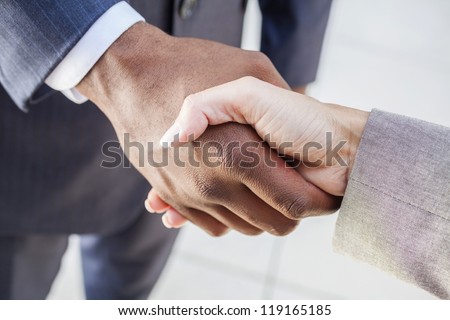 African American businessman or man shaking hands with a businesswoman or woman caucasian female colleague making a business deal