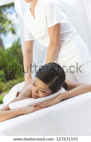 An Asian Chinese woman relaxing outside at a health spa while having a massage treatment