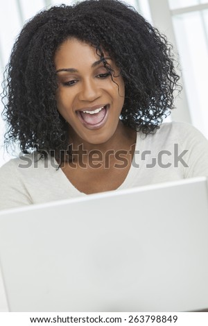 Beautiful African American woman open mouthed happy and surprised using her laptop computer.