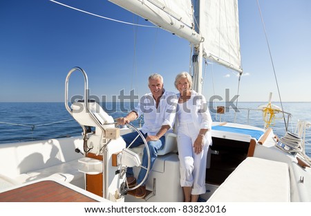 A happy senior couple sitting at the wheel of a sail boat on a calm blue sea