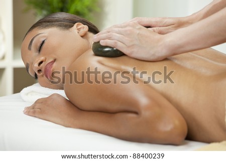 An African American  woman relaxing at a health spa while having a hot stone treatment or massage