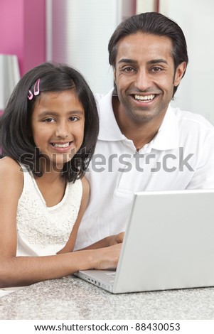 Asian Indian father and daughter, man and girl, using laptop computer in the kitchen at home