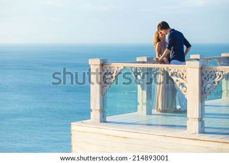 Couple posing on a balcony with ocean in the background