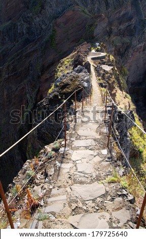 A narrow passage along a ridge with high cliffs both sides. Pico do Areeiro to Pico Ruivo hiking trail, Madeira, Portugal.