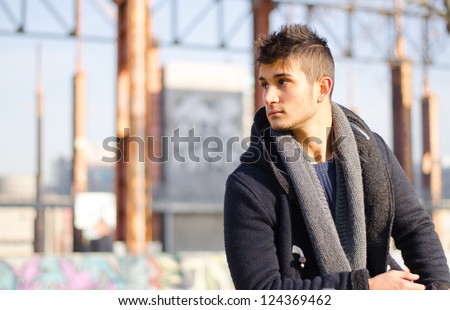 Handsome young man in urban or industrial setting looking to a side. Large copy-space.