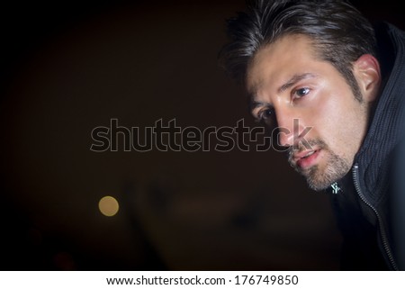 Attractive young man portrait at night, looking off camera