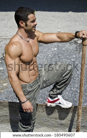 Muscle man shirtless outdoors in building site. Construction worker
